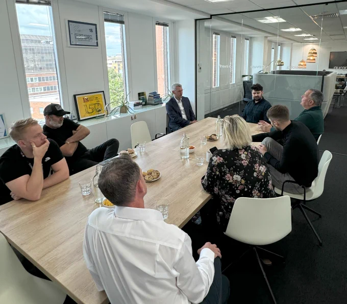 7 representatives from Inv Group and its subsidiary companies meet with WIll Forster, MP for Woking, sitting around a table in the board room in the Woking office.