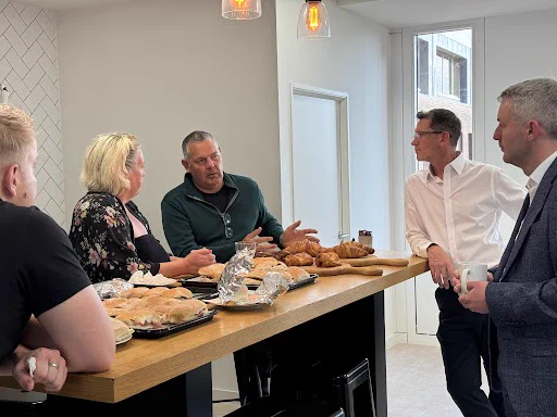 Will Forster, Liberal Democrat MP for Woking, Fintan Galvin, Paul Zimmerman and Alison Galvin, MBE are chatting across a table in the Inv Group Woking HQ.
