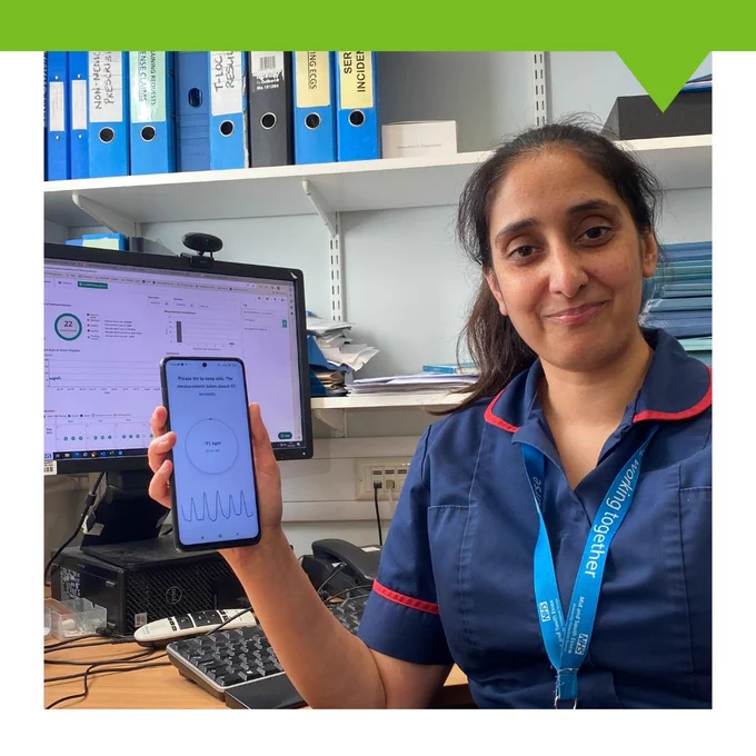 Member of staff smiling holding a phone up to display app.