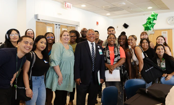 Group of students posing with Rush University President Robert Higgins, MD, in a classroom setting.