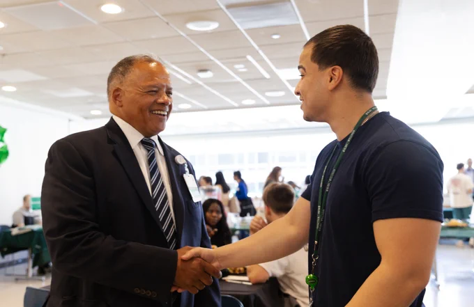 Rush University President Robert Higgins, MD, shakes hands with a student.