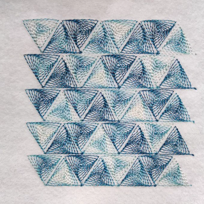 A stitched pattern made of up lines of triangles, where each triangle is is filled with a swirling pattern of smaller triangles. It uses variegated thread so the triangles appear in different colours. 