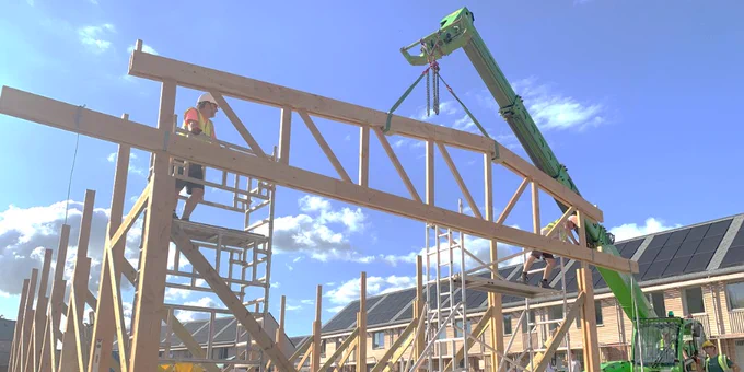 Image of on-site construction showing timber trusses being placed into position