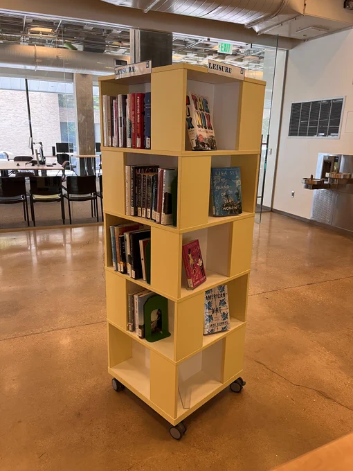 A yellow display shelf with books from RLB Library's leisure reading collection