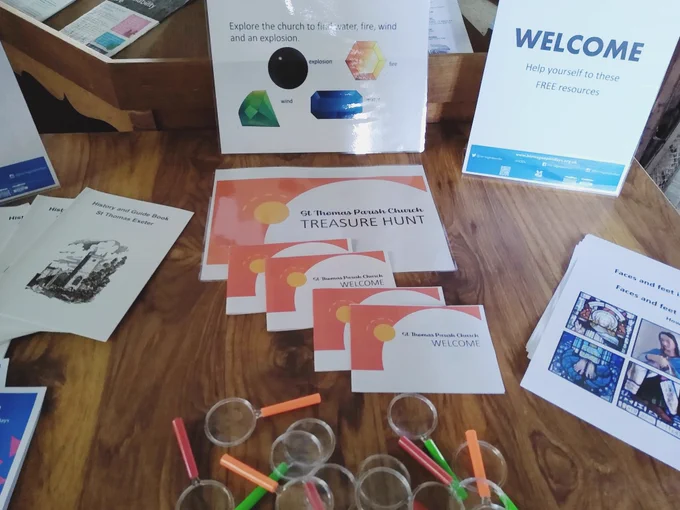 Photo showing a table with guide books, quiz sheets, welcome notices and small magnifying glasses. All ready for the Heritage Open Day tomorrow at St Thomas Parish Church between 11-3pm.