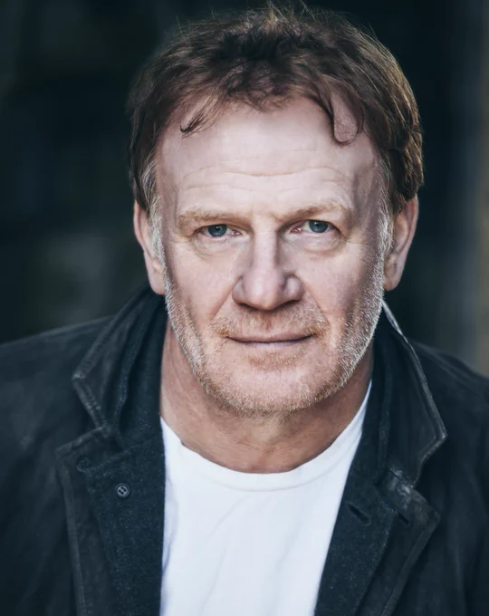 A headshot of Welsh actor Mark Lewis Jones who is looking directly towards the camera.