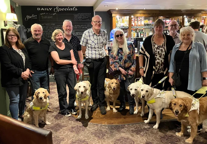 A group of six guide dogs , their owners and supporters 