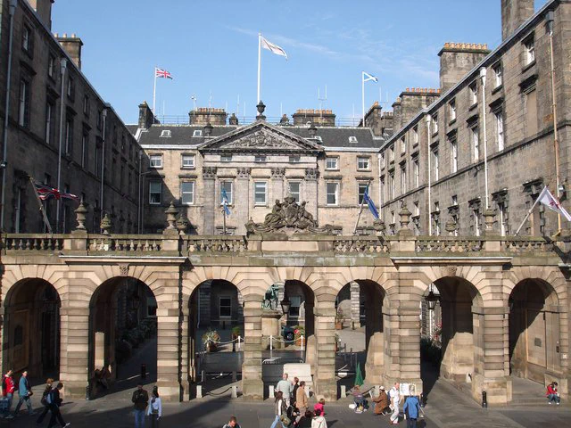 Exterior of the City Chambers on the High Street in Edinburgh on a sunny day. Lots of people walk past the entrance to the building.