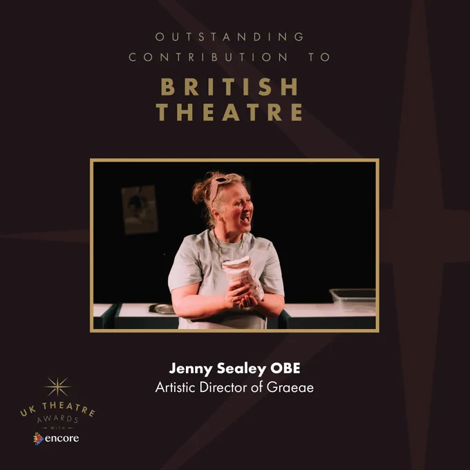 Text reads: UK Theatre Awards Outstanding Contribution to British Theatre, Jenny Sealey OBE, Artistic Director of Graeae. 
Image shows: Jenny Sealey smiling. She is holding a bag of flour, wearing a grey t-shirt and has a pair of pink sunglasses on top of her head.