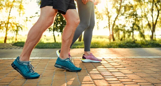 Hier zijn twee sportende mensen te zien. Ze doen aan hardlopen op een stenen weg. Alleen benen zijn te zien.