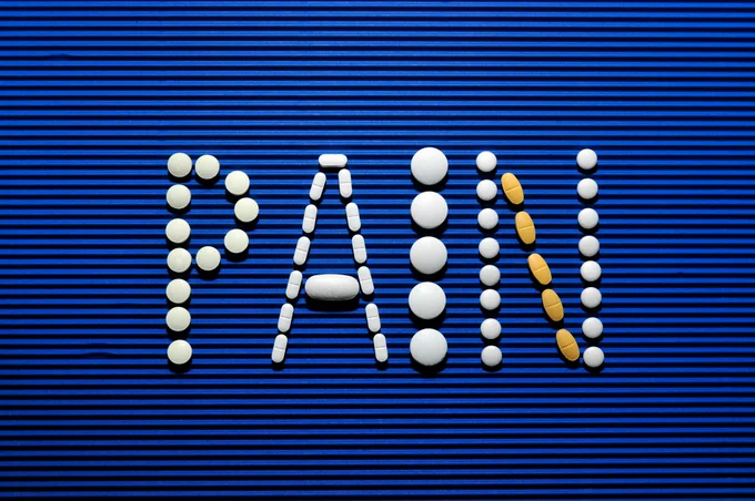 Medical pills sell out the word 'PAIN' on a blue background