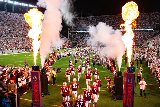 The Virginia Tech Hokies football team runs into Lane Stadium during a night game during Enter Sandman.