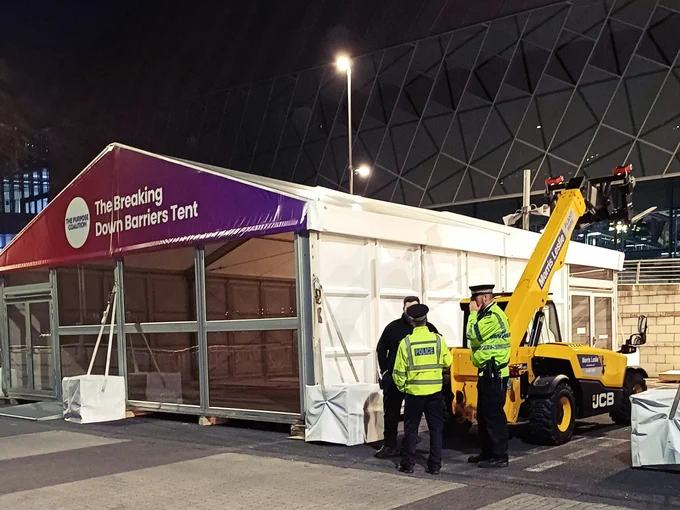 Project Servator officers speaking with contract staff outside ACC Liverpool event-site build at night.