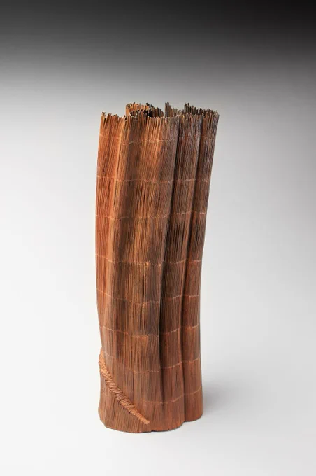 A copper toned undulating tall vessel made of thin metal clustered together with horizontal sectional striations.
