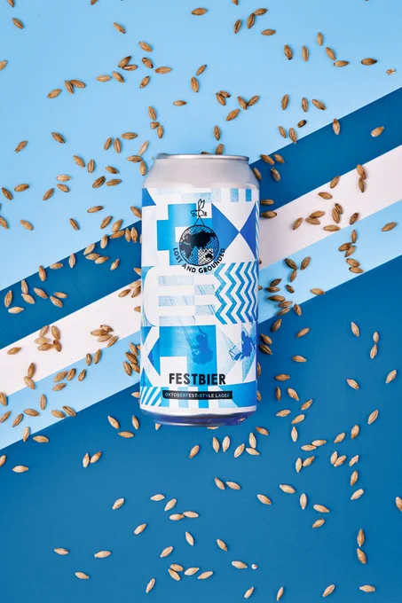 Can of our Festbier with spinkles of malt around it.