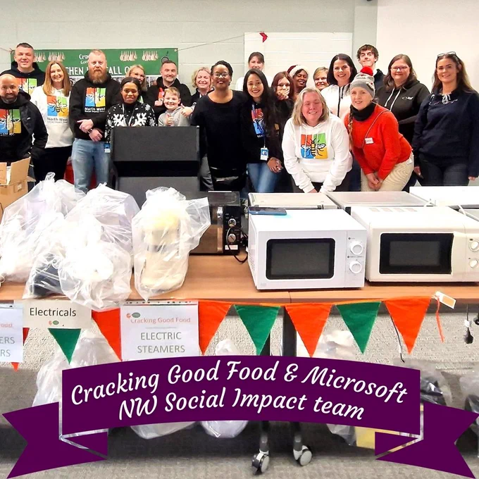 Cracking Good Food image. A group of volunteers stood around a table with donations of cooking equipment and food.