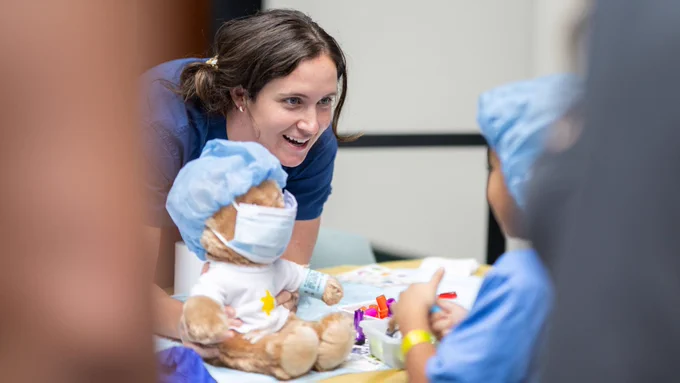 An employee showing a child a teddy bear.