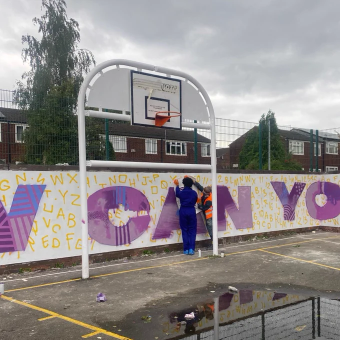 A child contributing art to the mural at Appleford Drive in Cheetham Hill