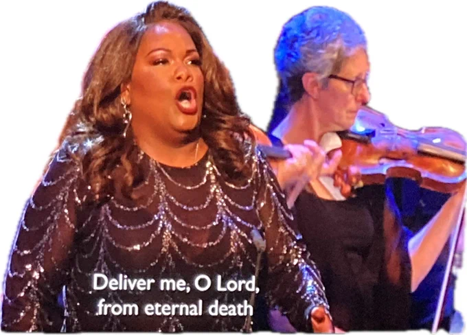Screengrab from a July 2024 Proms performance of Verdi’s Requiem. American soprano Latonia Moore, clad in a glittering grey dress, is singing passionately with a violinist playing in the background

Moore is singing in Latin. The English subtitle reads “Deliver me, O Lord, from eternal death”