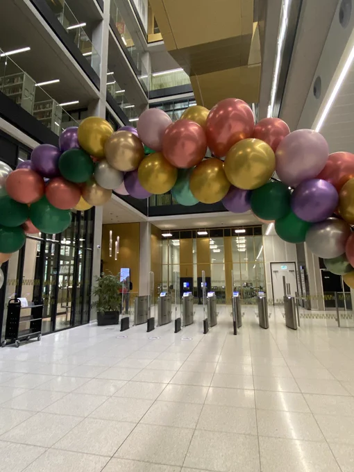 The turnstile gates at the Main Library entrance. In the foreground is a balloon arch with multicoloured balloons
