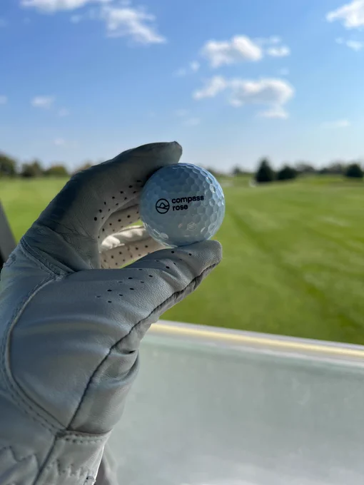 A golf ball with the Compass Rose logo on the green. 