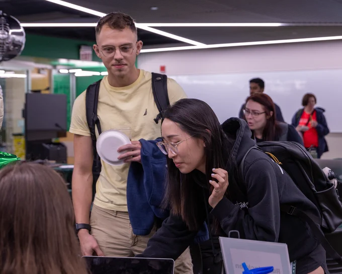 Two Rush students talking with a student organization, with others in the background engaging in various activities.
