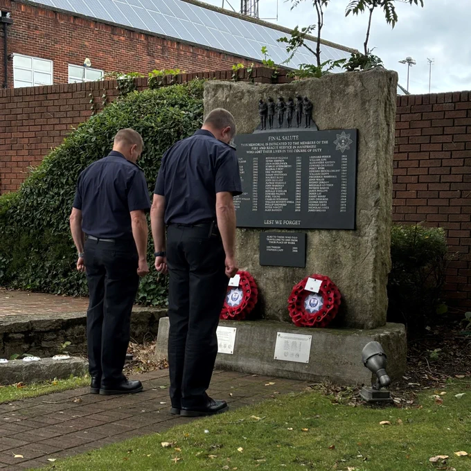 Two firefighter saluting a firefighter memorial statue 