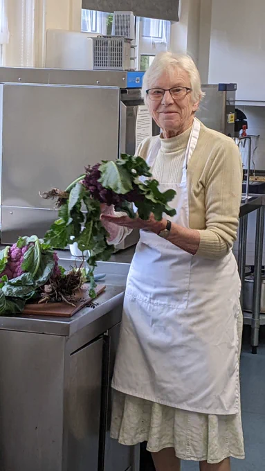 A volunteer chef at Weston Welcome Hub holding the purple cauliflower.