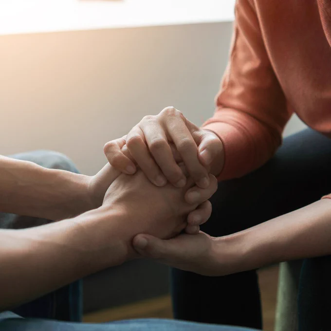 Two pairs of hands holding each other supportively