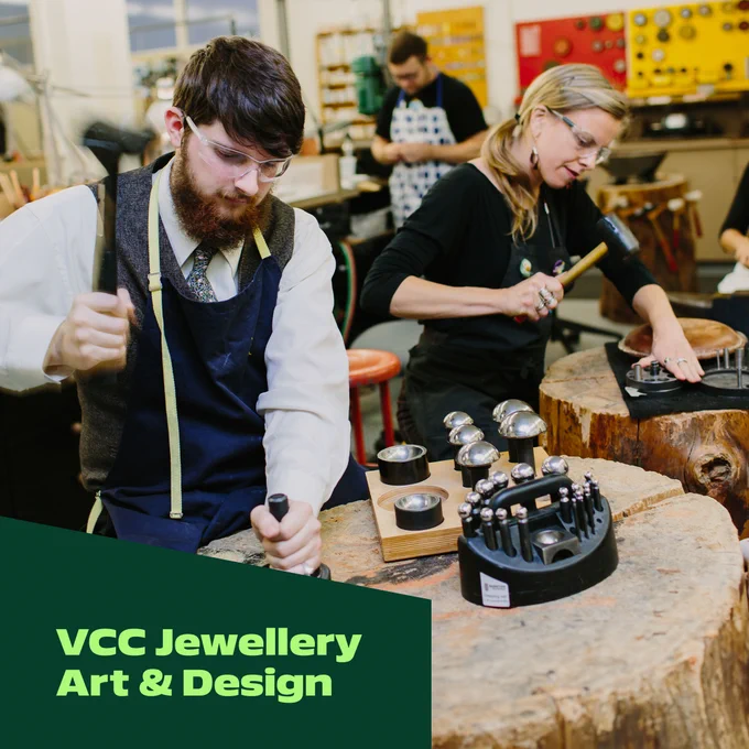 Two jewellers working on wooden workbenches with a variety of jewellery making tools, wearing protective glasses, focussing intensely. 