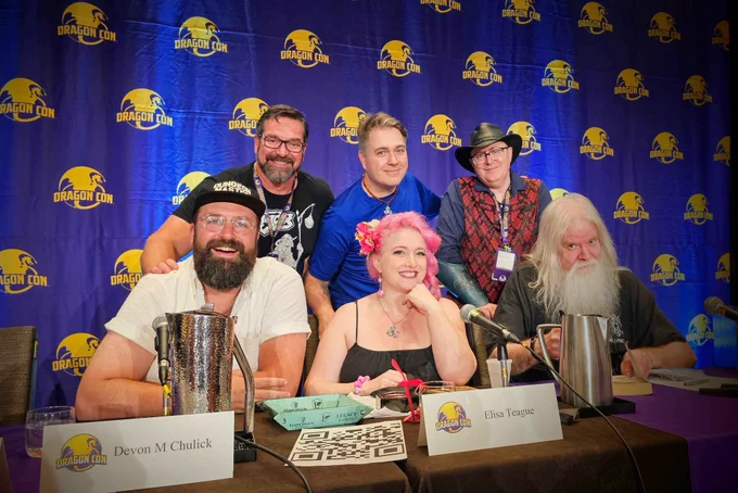 Group of 6 people in front of a purple DragonCon background.