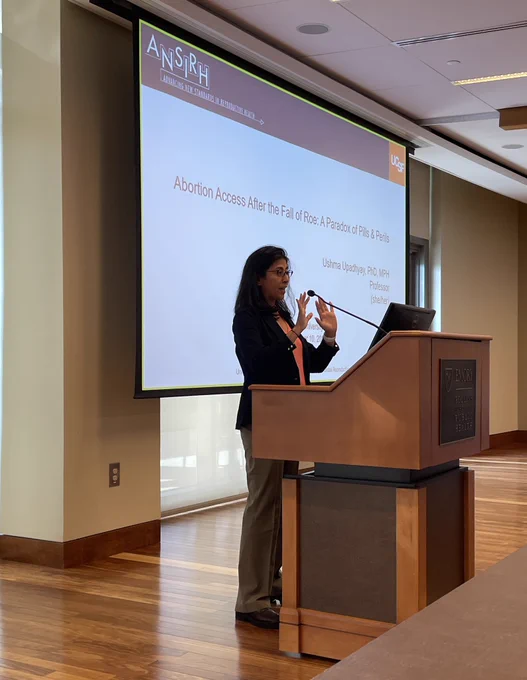 Dr. Ushma Upadhyay presenting at a lectern