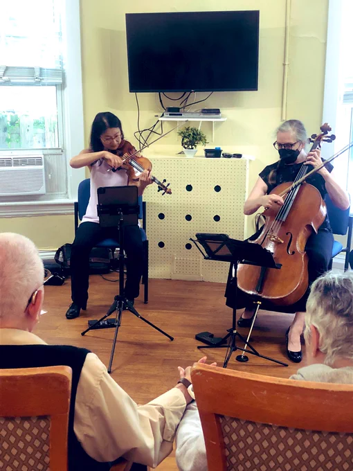 Cellist and violinist playing their instruments as a man and woman, holding hands, watch