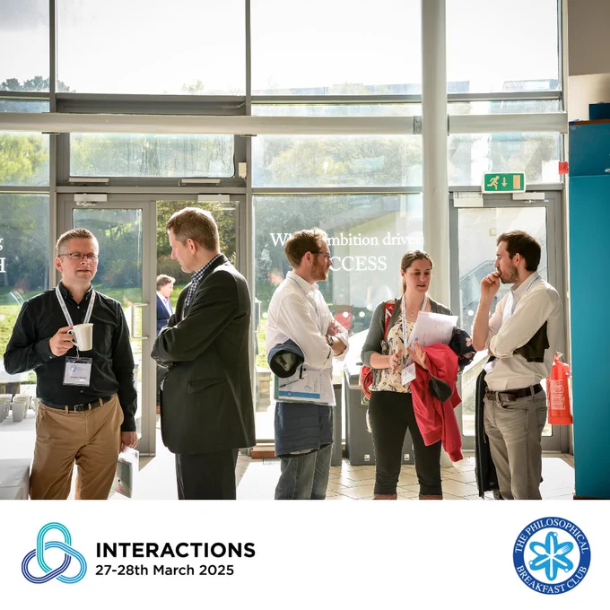 A photo of five people standing in a light atrium, chatting. Below is a white band with the PBC's logo to the right, and the event INTERACTIONS logo to the left, showing the conference dates 27-28th March 2025.