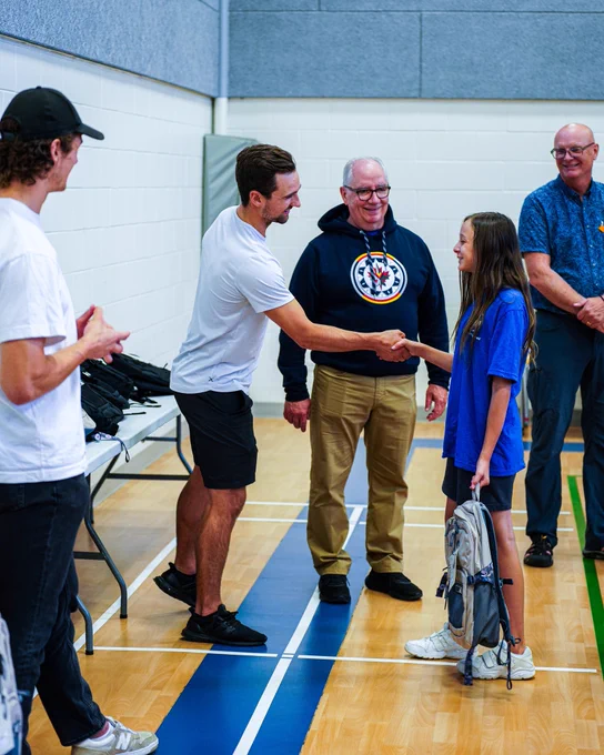 Neal Pionk gifting a backpack to a Gonzaga Middle School student.