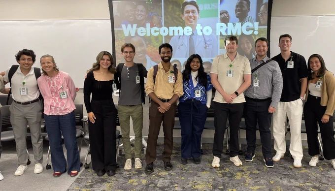 Group of first-year Rush Medical College students smiling, standing in a row at a 'Welcome to RMC!' event.