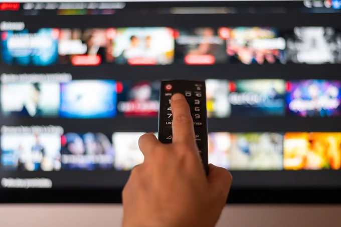 Hand with remote control pointing at a tv screen