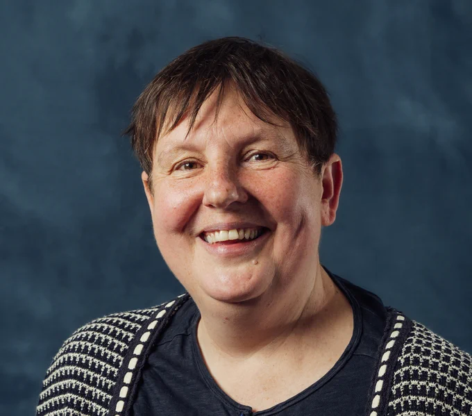 A photo of Professor Emma Smith, smiling against a blue-grey background. 