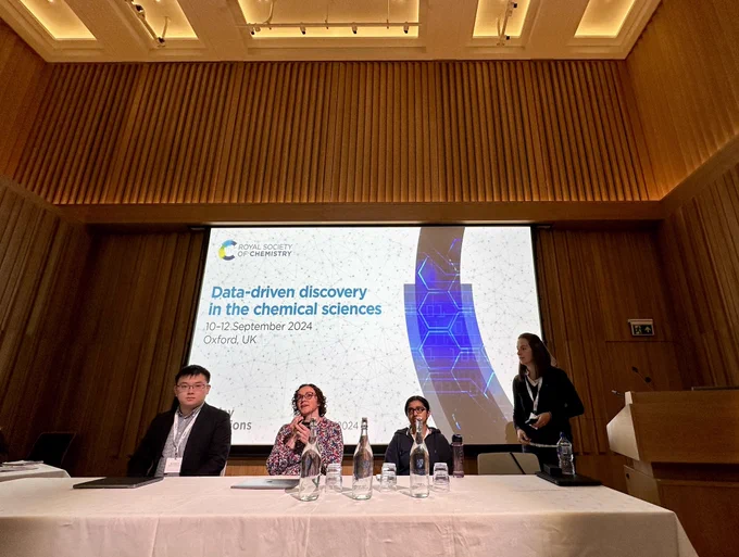 A photo of the presenters from the first session on Wednesday, and the session chair, in front of a screen showing the event title