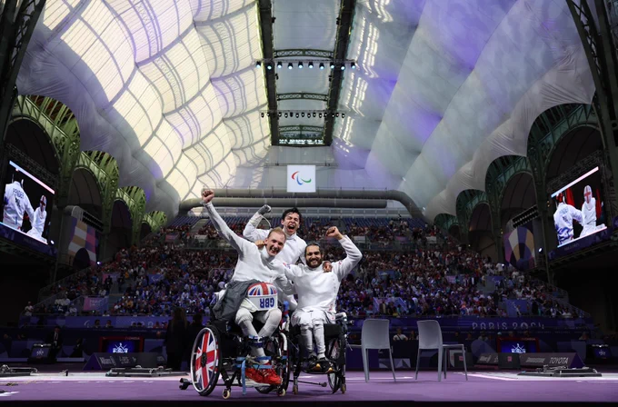Three wheelchair fencers celebrate in the grand Palais