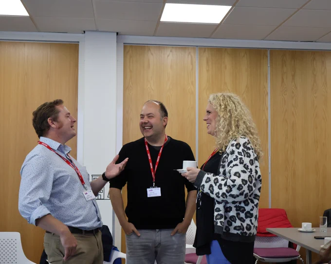Three people stood together laughing at the Thinking Differently Peer Meeting.