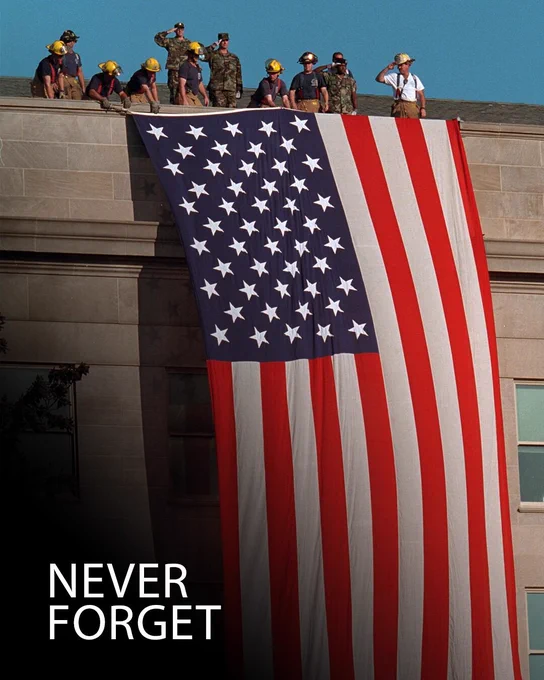 First responders standing on the roof of a large stone building unfurling the flag, military personable standing by saluting the flag, “never forget”