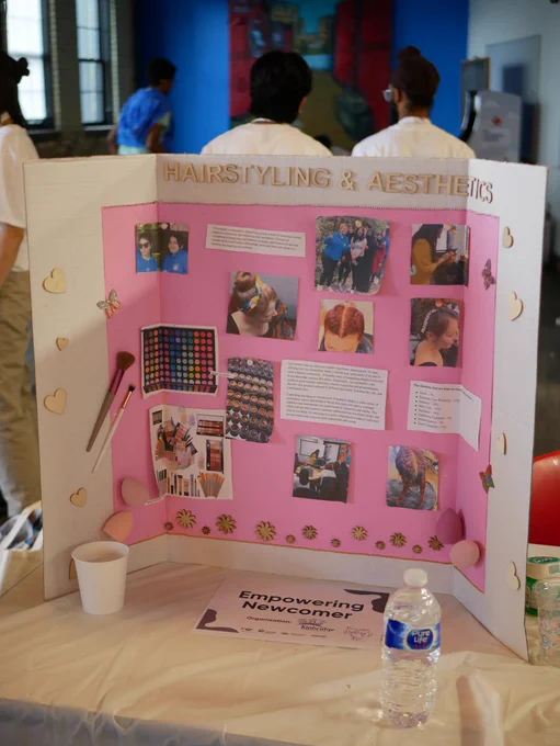 A pink poster board that says "hairstyling and aesthetics." pictures of makeup, hair, smiling women, words, and text.