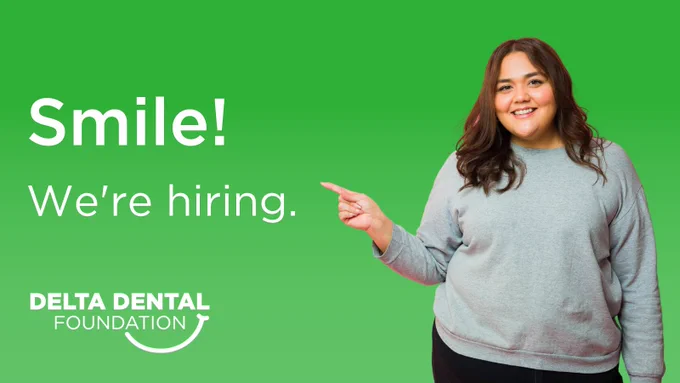 White woman in a sweater with pointing to text that reads, "Smile! We're hiring." She stands in front of a green background. The Delta Dental Foundation logo is in the bottom left corner. 