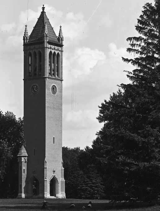 Black and white photo from 1906 shows Campanile with darker clock face and no sidewalks around it. 