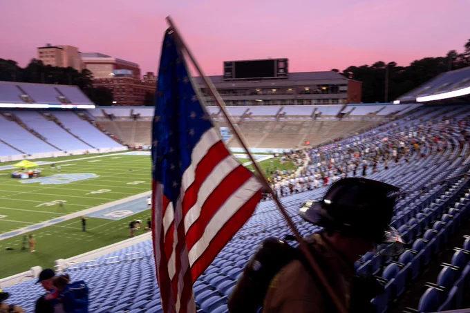 A firefighter carries the American flag up the stairs of Kenan Stadium at sunrise during the 9/11 Memorial Stair Climb at UNC