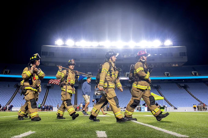 A group of firefighters walk across Kenan Stadium at sunrise during the 9/11 Memorial Stair Climb at UNC