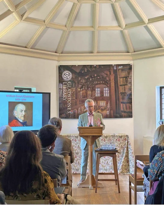 A scholar delivering a conference presentation at a podium