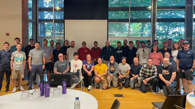 Group photo of Kraken Youth Hockey Association volunteer coaches in a meeting room.