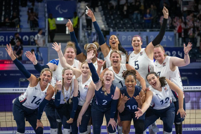 A group of people cheering near a volleyball net.